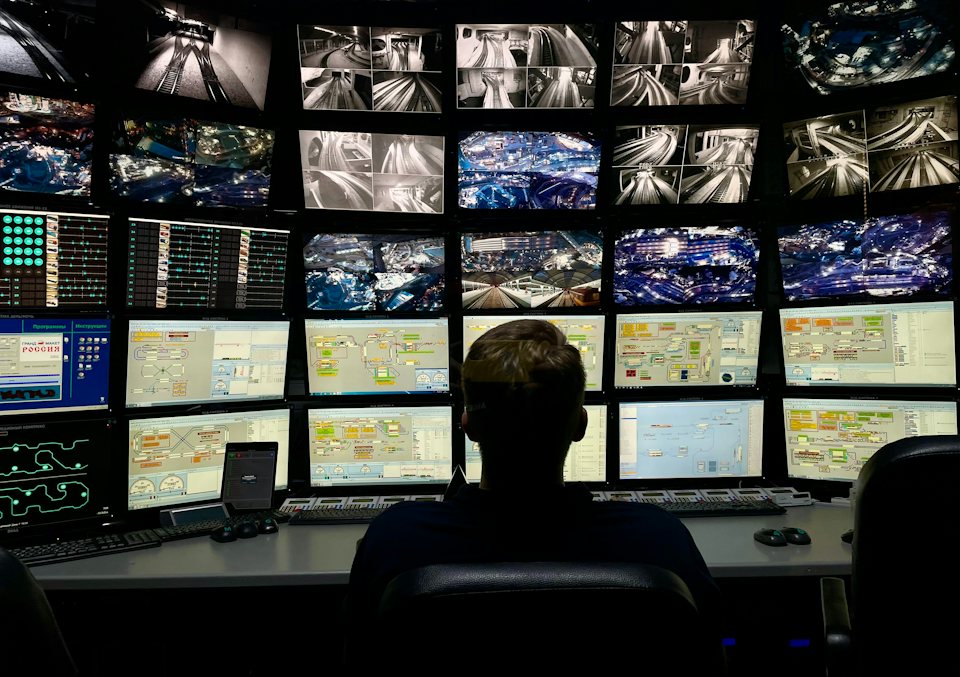 An operator monitoring a wall of CCTV screens in a security control room